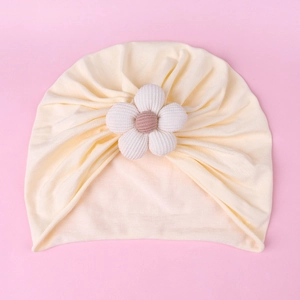 Detailed view of baby knot turban hat in cream white cotton knit with 3D floral accent