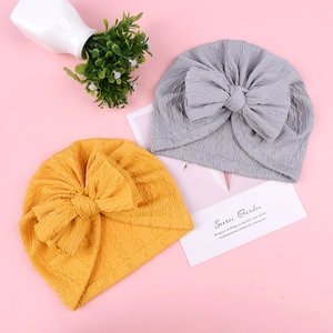 Texture détaillée des bonnets tricotés pour bébé avec de grands nœuds gris et jaunes