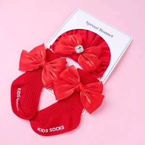 Détail de chaussettes bébé rouges à nœuds et bandeau assorti avec strass brillants