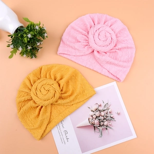 Detailed view of pink and ginger yellow knotted infant turbans made of elastic knit fabric