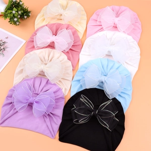 Detail of baby lace bow hats in multiple colors including soft pink and beige