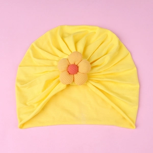 Detail of yellow baby turban hat featuring a 3D knitted flower on soft fabric