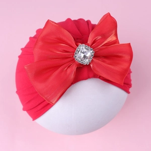 Détail du bonnet turban rouge pour bébé avec grand nœud en satin et ornement diamant