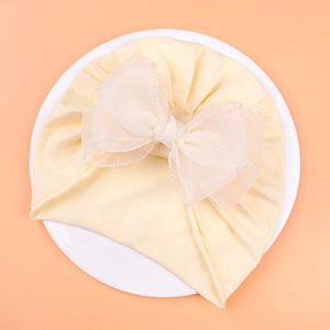 Detailed view of sweet light yellow baby turban hat with oversized white lace tulle bow