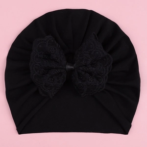 Macro view of baby turban hat featuring a large black lace floral bow decoration