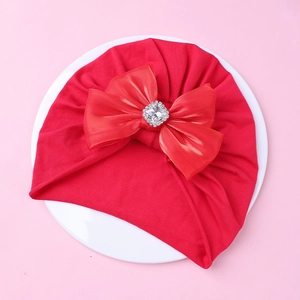 Détail du bonnet turban bébé rouge avec grand nœud en satin et cristal étincelant