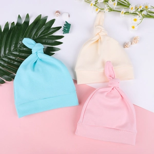 Flat lay of soft knit baby knotted hats in sky blue, beige and pink pastel colors