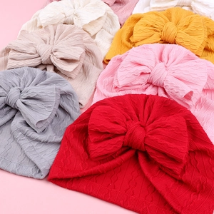 Détail du tricot torsadé et du grand nœud sur les bonnets turbans doux pour bébés