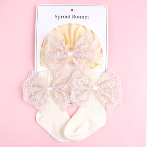 Detail showing baby sprout bonnet and ribbed socks with pink lace bows on pink background
