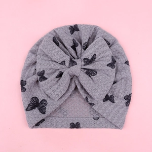 Detail of baby turban hat featuring grey waffle fabric with black butterfly prints and bow