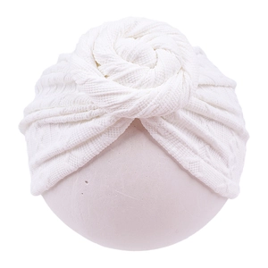 Close-up of white waffle knit baby turban hat with a stylish donut knot on plain background