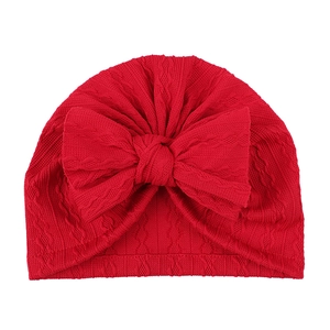Détail du bonnet tricoté rouge pour bébé avec grand nœud et motif jacquard texturé