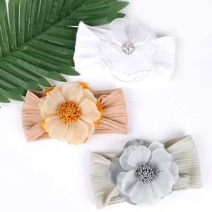 Gros plan détaillé de trois bandeaux élastiques pour bébés avec fleurs en tissu et strass