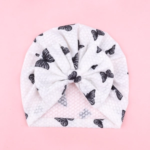 Infant turban hat with black butterfly print and large bow on a soft white knit base