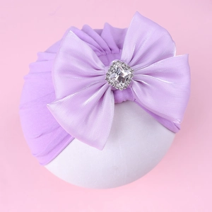 Détail d'un turban violet pour bébé avec un grand nœud en soie et un diamant carré brillant