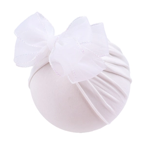 Macro detail of white baby bonnet with large lace bow and shiny iridescent edge trim