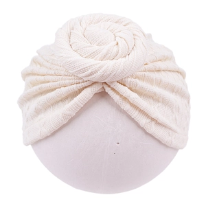Close-up of cream knit baby turban hat with a donut knot and waffle texture fabric