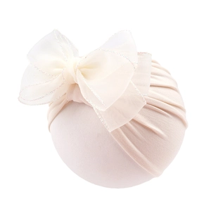 Close-up of baby turban hat featuring a large organza double bow and ruffled edges