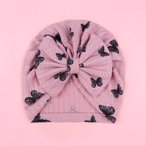 Detailed view of pink waffle knit baby turban hat with black butterfly prints and big bow