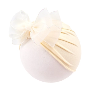 Detail of baby headband with oversized white organza double bow and soft beige fabric