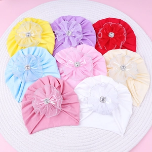 Close-up of baby turbans with lace flowers, rhinestones, and ribbons in eight soft colors