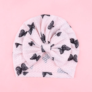 Close-up of pink breathable infant turban hat with large bow and black butterfly prints