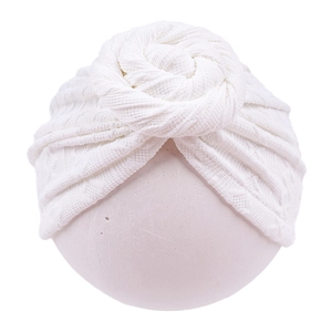 Detailed view of white baby turban with hand-knitted knot design and soft fabric texture