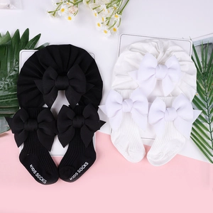 Set turbante e calzini per neonati con grandi fiocchi su sfondo rosa e bianco