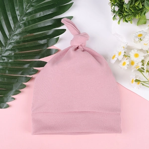 Detailed view of pink knotted baby beanie made of soft ribbed knit cotton fabric
