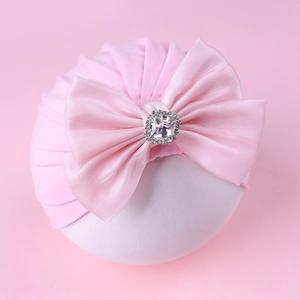 Détail du bonnet turban rose pour bébé avec un grand nœud et une boucle en diamant brillant