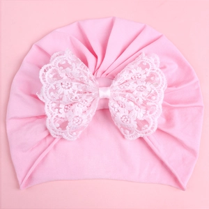 Pink newborn knit turban hat with large white lace bow detail for baby photography