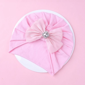 Détail du bonnet en coton pour bébé avec nœud en dentelle rose et strass étincelants