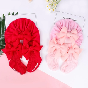 Dettaglio di turbanti per neonati rossi e rosa con calzini a fiocco abbinati in set regalo