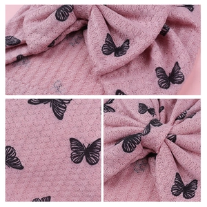 Detail of pink waffle knit baby headband with butterfly pattern and bow texture