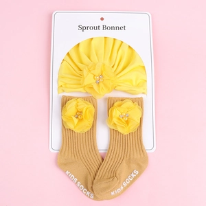 Détail du bonnet de bébé jaune et des chaussettes assorties avec fleurs décoratives