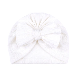 Vue détaillée du bonnet blanc pour bébé en maille côtelée avec un grand nœud décoratif