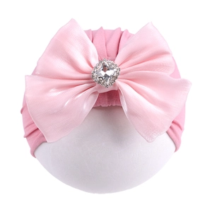 Détail du bonnet turban rose pour nouveau-né avec grand nœud en soie et boucle diamant