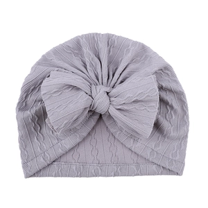 Détail du bonnet lilas pour bébé avec grand nœud et texture en tricot torsadé doux