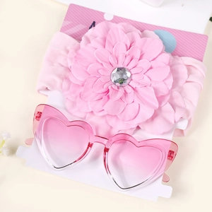 Détail de l'ensemble bandeau bébé à fleur rose et lunettes de soleil coeur sur carte