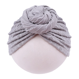 Close-up of light gray knitted infant turban hat with decorative top knot detail
