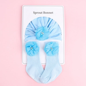 Détail d'un ensemble bonnet et chaussettes en coton bleu avec fleurs en mousseline