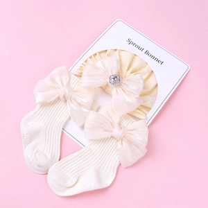Détail de chaussettes et bandeau bébé en coton crème avec nœuds en soie et cristal