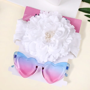 Détail du bandeau bébé en jacquard blanc avec fleur de perles et lunettes de soleil cœur