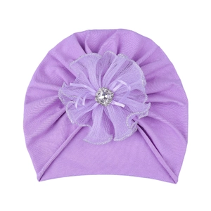 Detail of baby turban hat with a large purple mesh flower and a crystal center