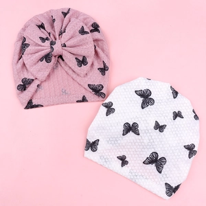 Detail showing soft knit baby beanies with butterfly prints and a large pink bow decoration
