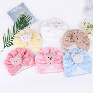 Flat lay of six colorful textured baby beanies featuring 3D plush bear patches for infants