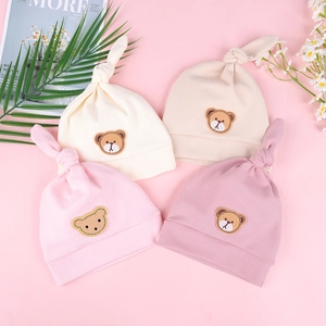 Detailansicht von vier Baby-Knotenmützen aus Baumwolle mit süßem Bären-Patch in Pastell