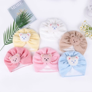 Detail view of colorful baby beanies with cute plush bear decor and soft ribbed texture