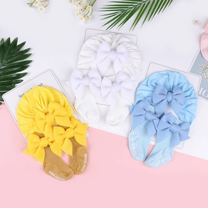 Dettaglio del set cappello a turbante e calzini per neonati con grandi fiocchi in maglia
