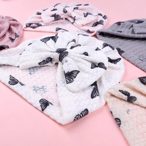 Detail of baby turban hats with butterfly pattern and oversized bows in waffle knit fabric